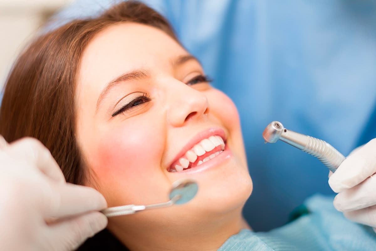 Paciente sonriendo en el sillón dental durante un tratamiento de rehabilitación oral